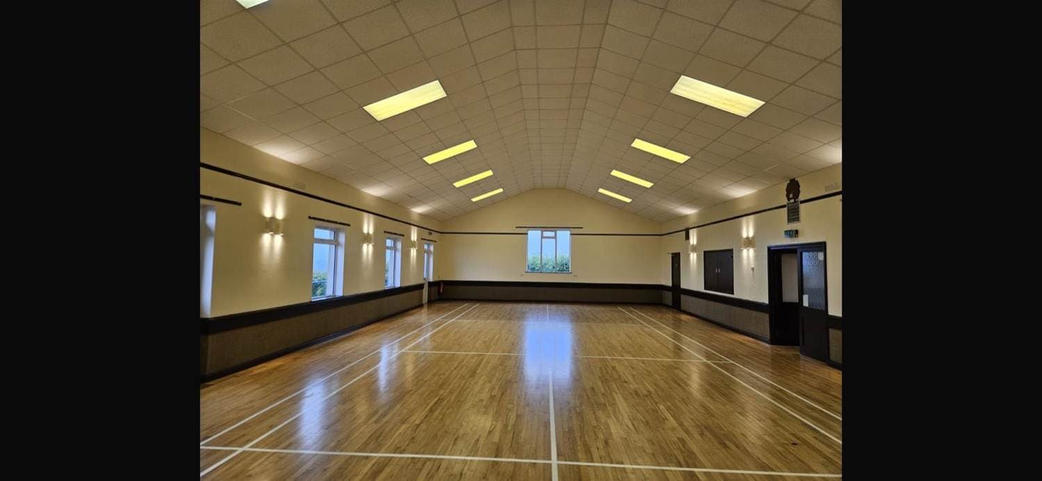 Refurbished village hall — repainted walls and restored timber floor under a vaulted ceiling